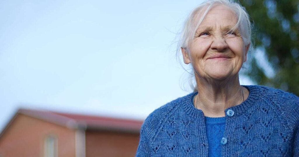 Mulher idosa sorrindo, representando a longevidade e saúde, com a caixa de metformina ao lado.