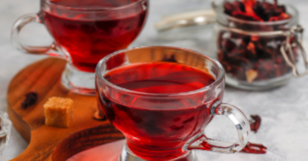 Chá de hibisco em uma xícara com flores de hibisco ao fundo