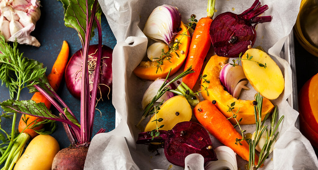 Mesa com diversos alimentos saudáveis que fortalecem o sistema imunitário, incluindo cítricos, brócolos, alho, gengibre, espinafres, amêndoas, chá verde, papaia, frango e mariscos.